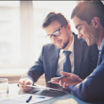 two workers in suits looking at an ipad