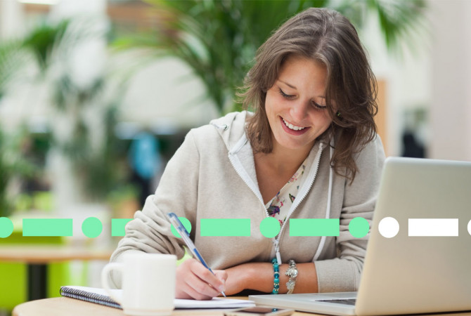 happy lady using laptop and writing notes